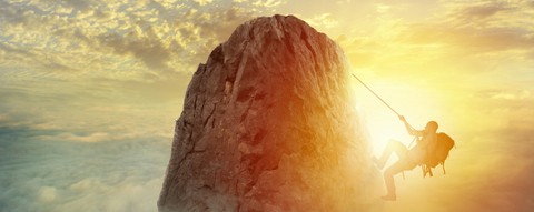Climber scaling down a rock face at sunset