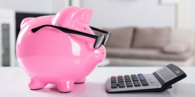 Piggy bank with glasses looking at a calculator