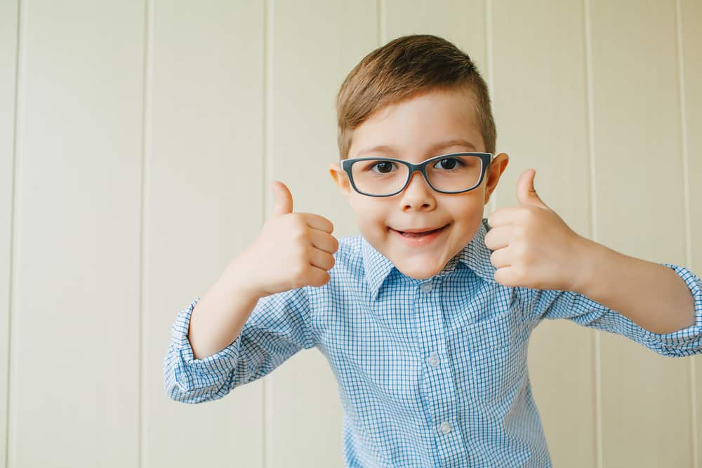 Small boy with glasses giving a thumbs-up