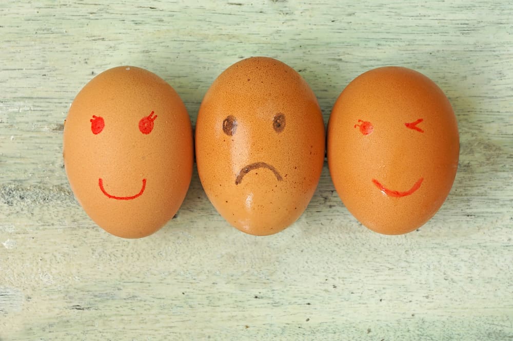 Three eggs with sad and smiling faces painted on them