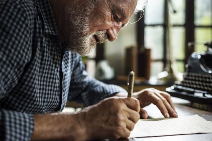 Older man writing in a notebook