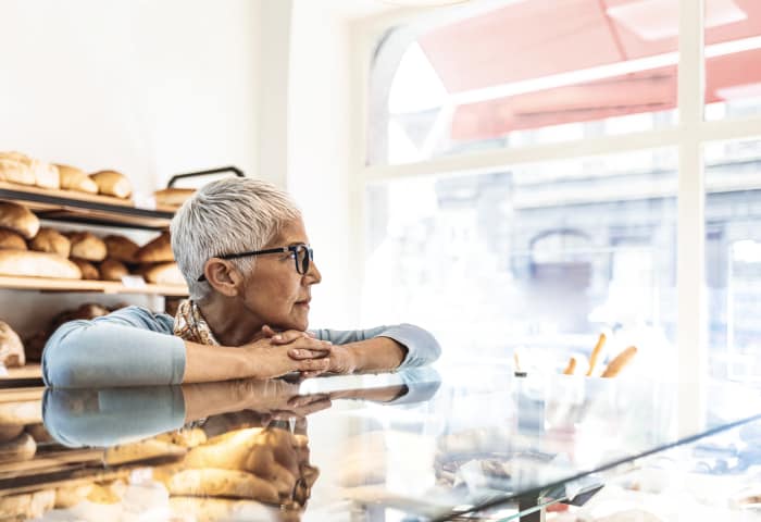 Thoughtful woman leaning on bakery counter thinking about pensions and the Autumn Statement