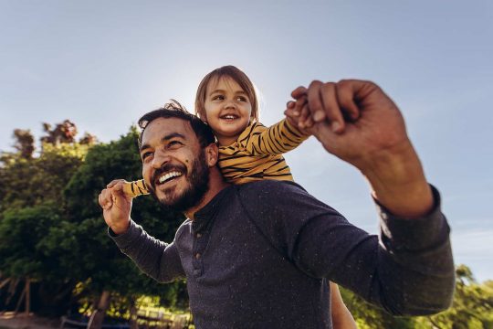 Man smiling with boy on shoulders