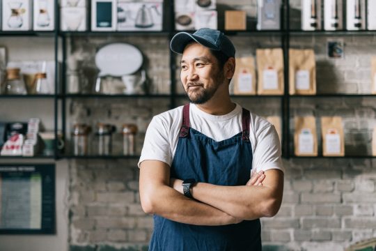 Japanese man smiling looking away from the camera with arms folded
