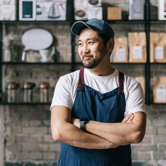 Japanese man smiling looking away from the camera with arms folded