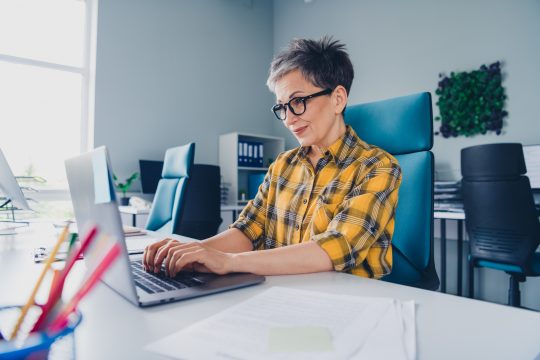 Mature white woman using laptop and smiling