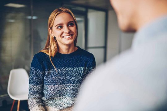 Woman smiling towards a man in an office setting
