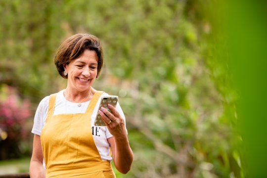 Mature white woman smiling while looking down at phone