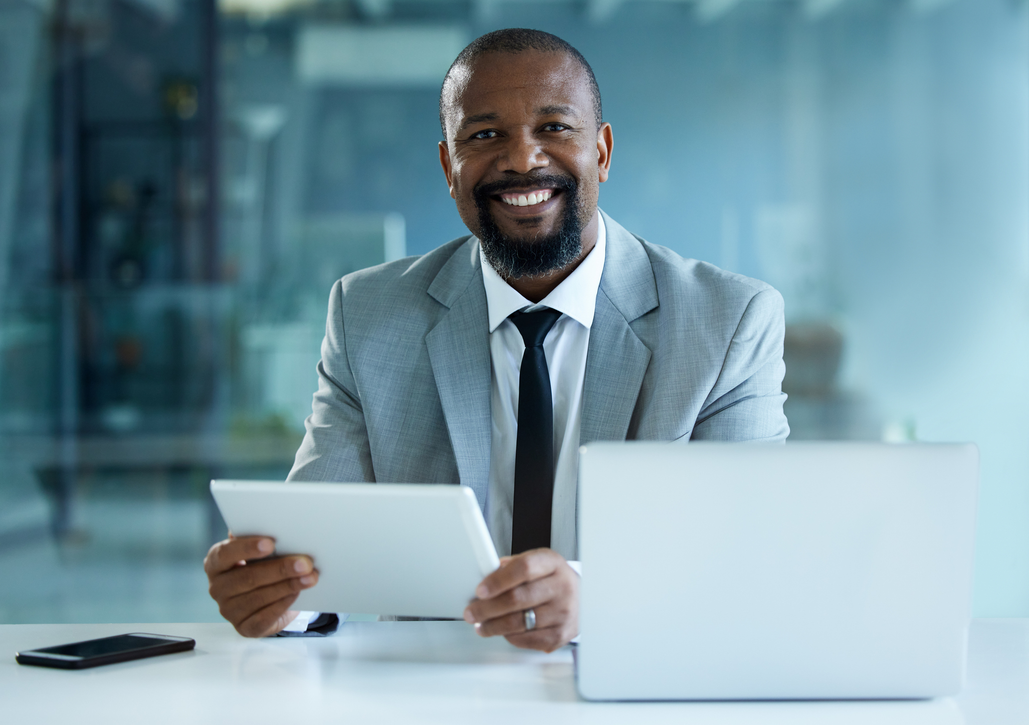 Portrait of a mature businessman working on a digital tablet and laptop in an office