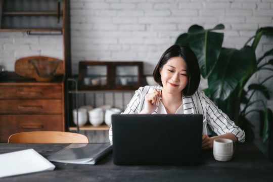 Young Asian woman smiling while using a laptop