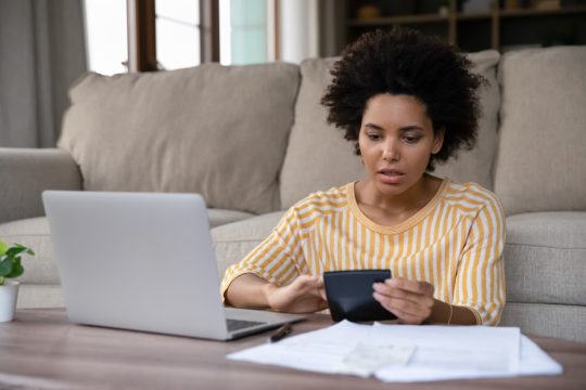 Surprised stressed young african ethnicity biracial woman calculating expenditures