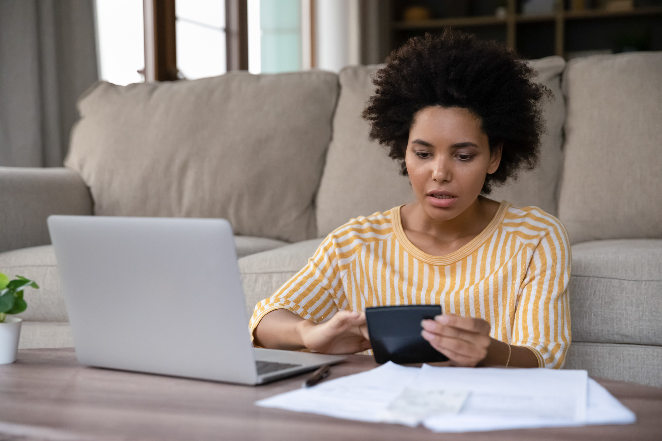 Surprised stressed young african ethnicity biracial woman calculating expenditures