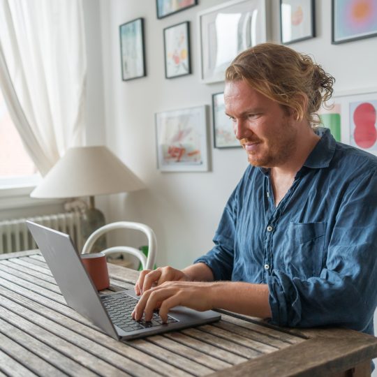 Man works on laptop at dining room table