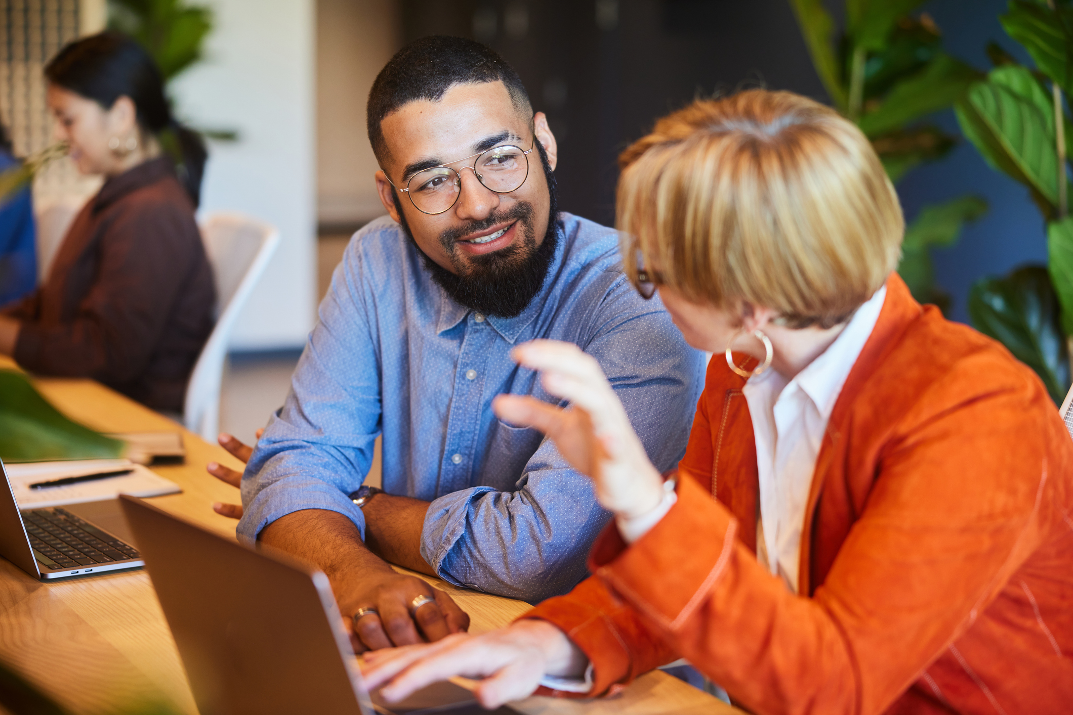 Two diverse businesspeople smiling and talking together while working