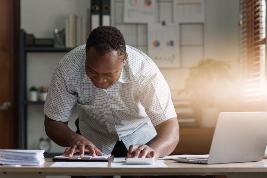 American African Businessman research and analysis with financial graph at office