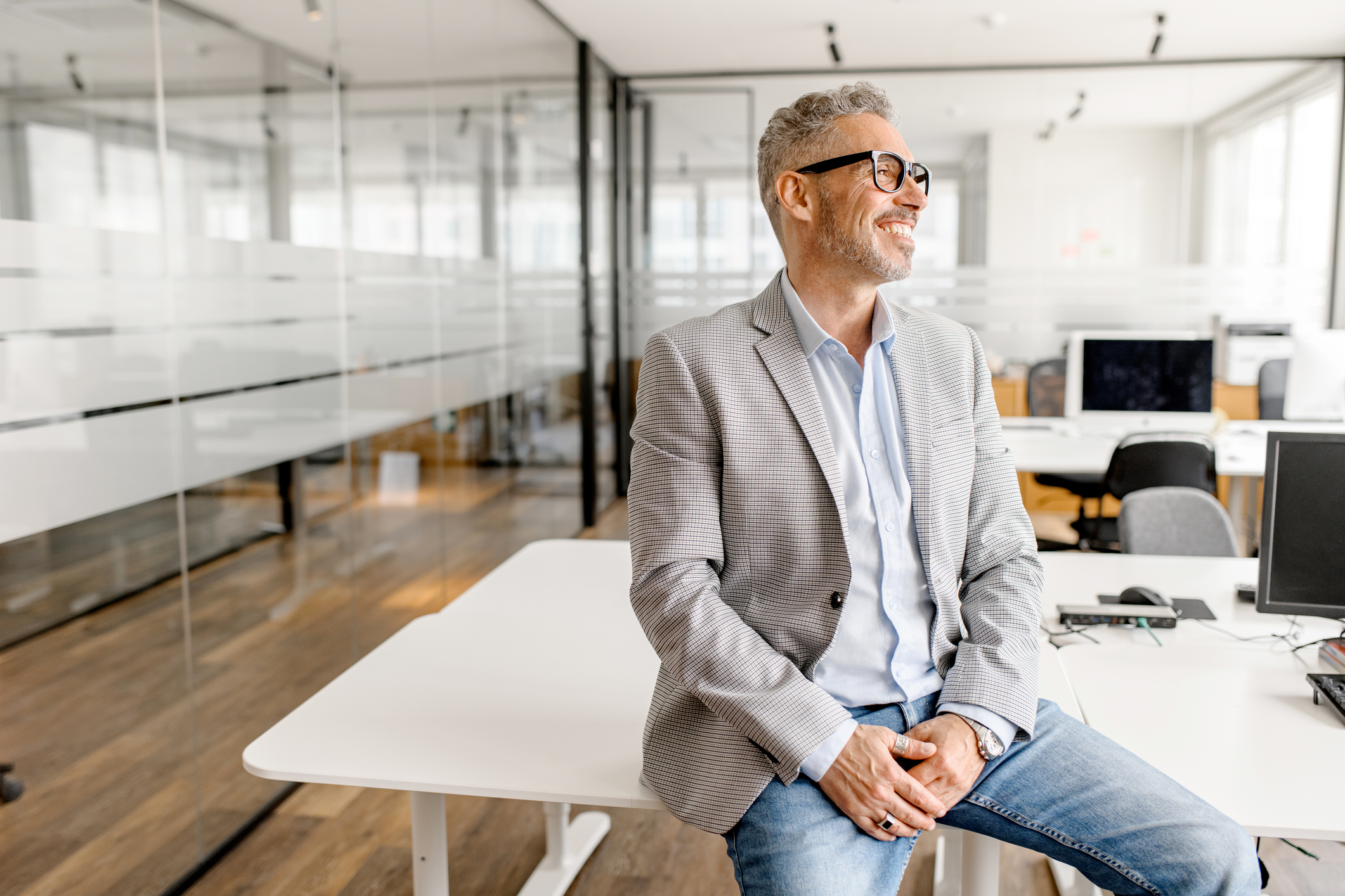 Middle aged businessman in formal wear leaned on the desk looking away