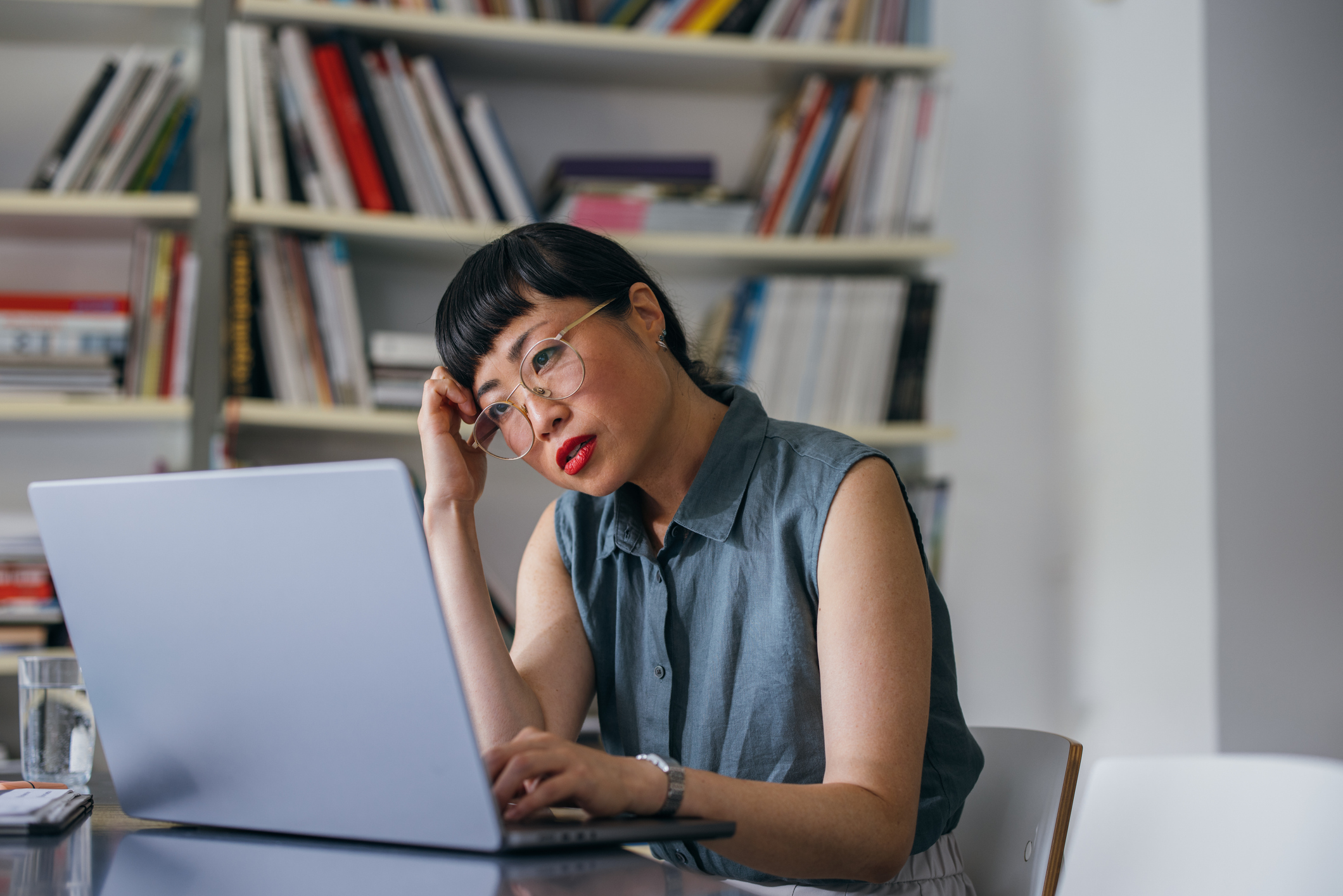 Middle aged Asian woman looking stressed looking at laptop