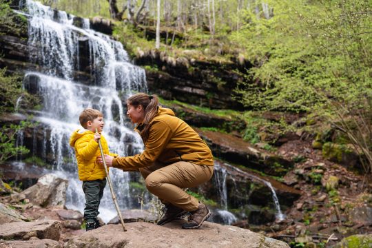Mother and son on a hiking trip by a waterfall