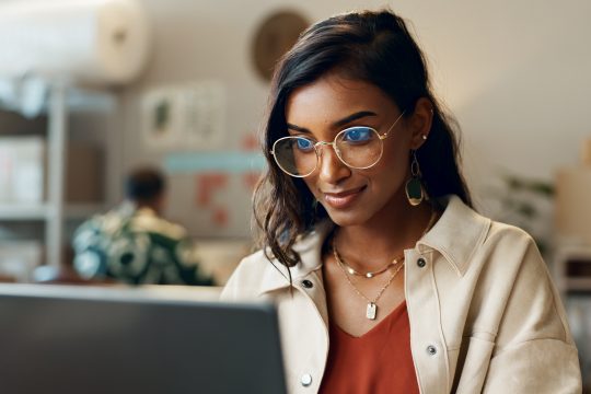 Woman reading on laptop at work for research
