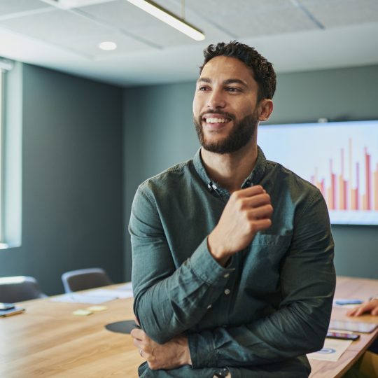 Confident young businessman standing in a modern office and smiling
