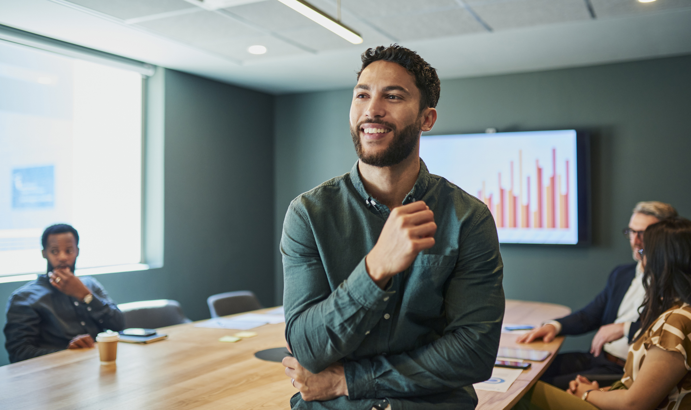 Confident young businessman standing in a modern office and smiling