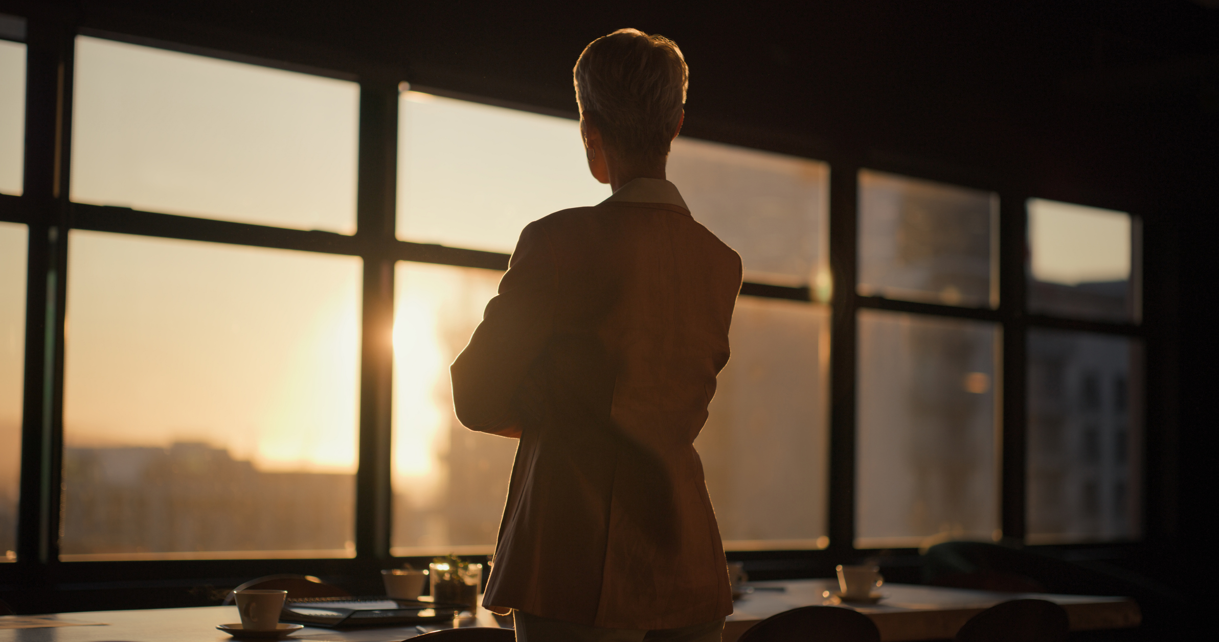 Sunset, window and back of woman in the office thinking, planning and brainstorming for project.