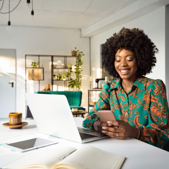 lady smiling using her smartphone and laptop