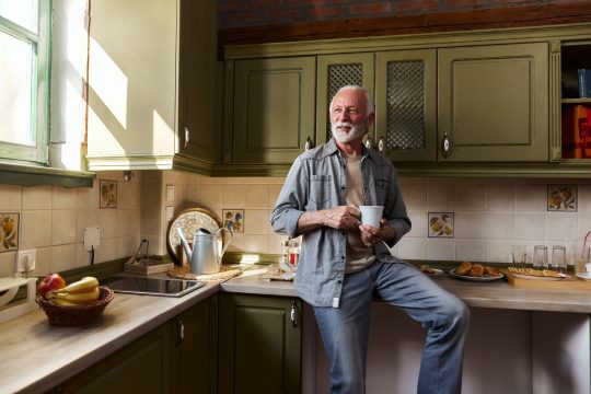 Happy mature man day dreaming during coffee time at home
