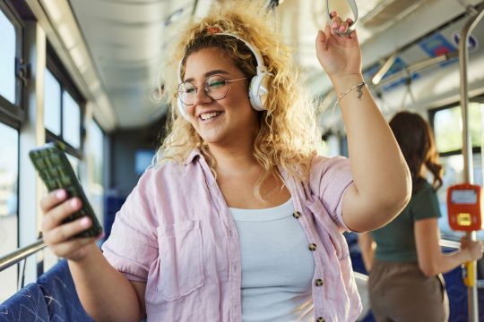 Woman listening music over cell phone in a bus