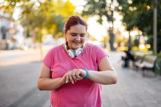 Woman checking fitness activity on the smartwatch after exercising in the park
