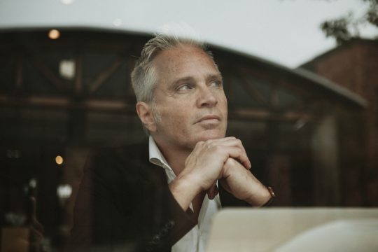 man looking out of a café window with a thoughtful expression