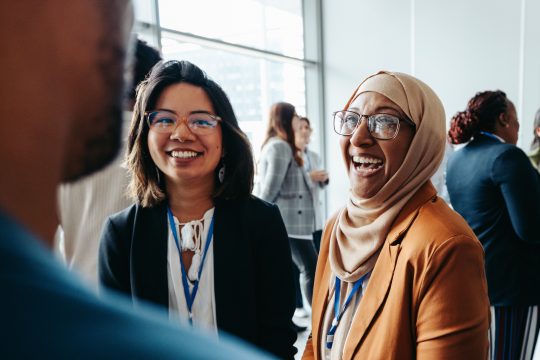 Female colleagues sharing happy smiles interacting at a corporate workshop