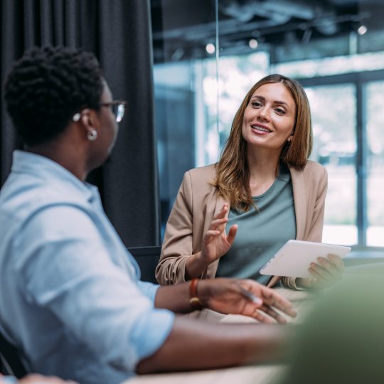 Woman smiling looking at two colleagues in a business meeting