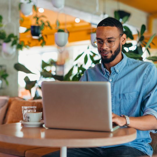 Young man sitting in coffee shop and using laptop