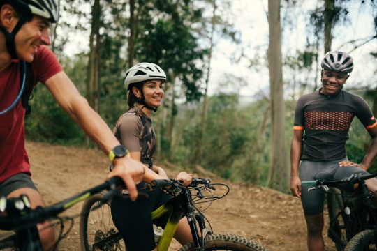 Group of three friends cycling together in the nature