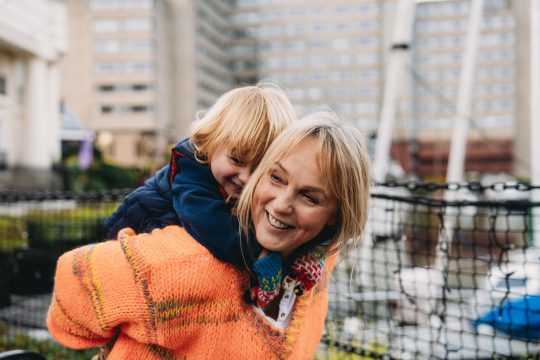 Grandmother giving piggyback ride to her grandson in a urban park
