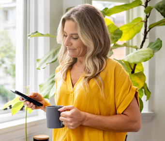 a woman using her phone next to green house plants