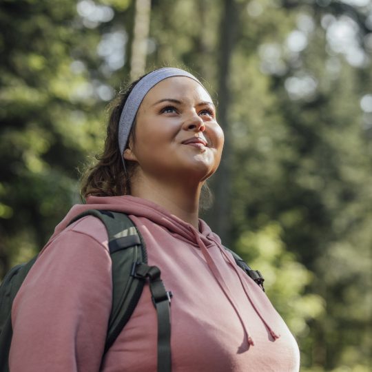 Happy woman with a backpack spending a day in nature, a portrait.