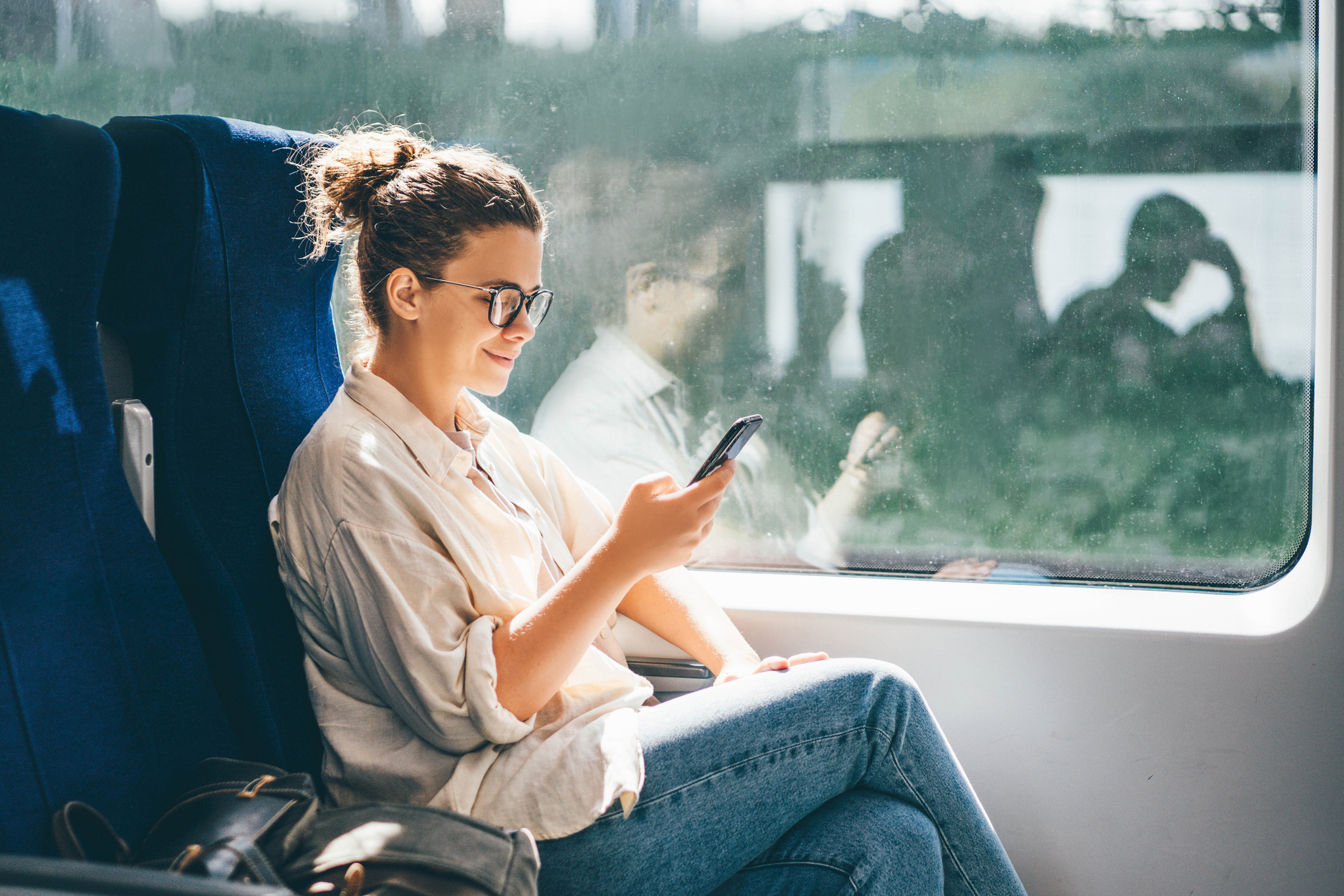 Young woman traveling by train and using phone
