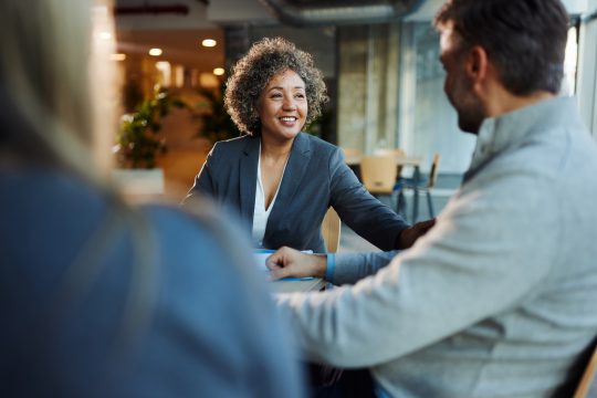 Happy insurance agent talking to her customers in the office