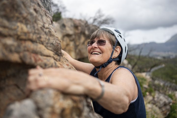 Mature woman rock climbing and smiling looking upwards
