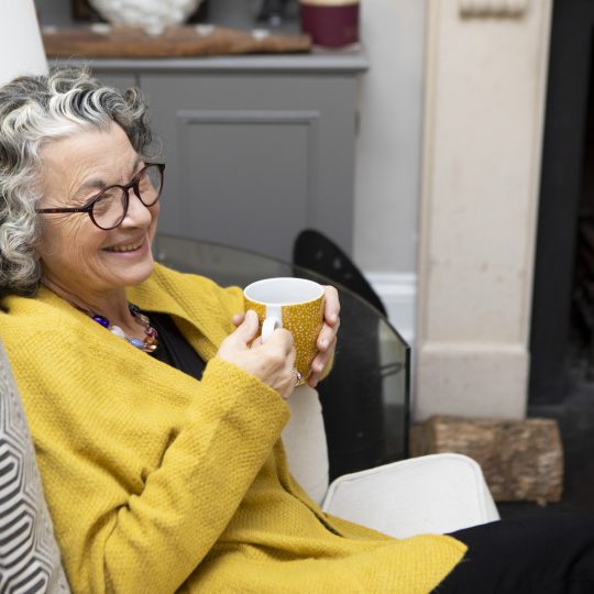 mature adult sitting by a fireplace in a living room at home