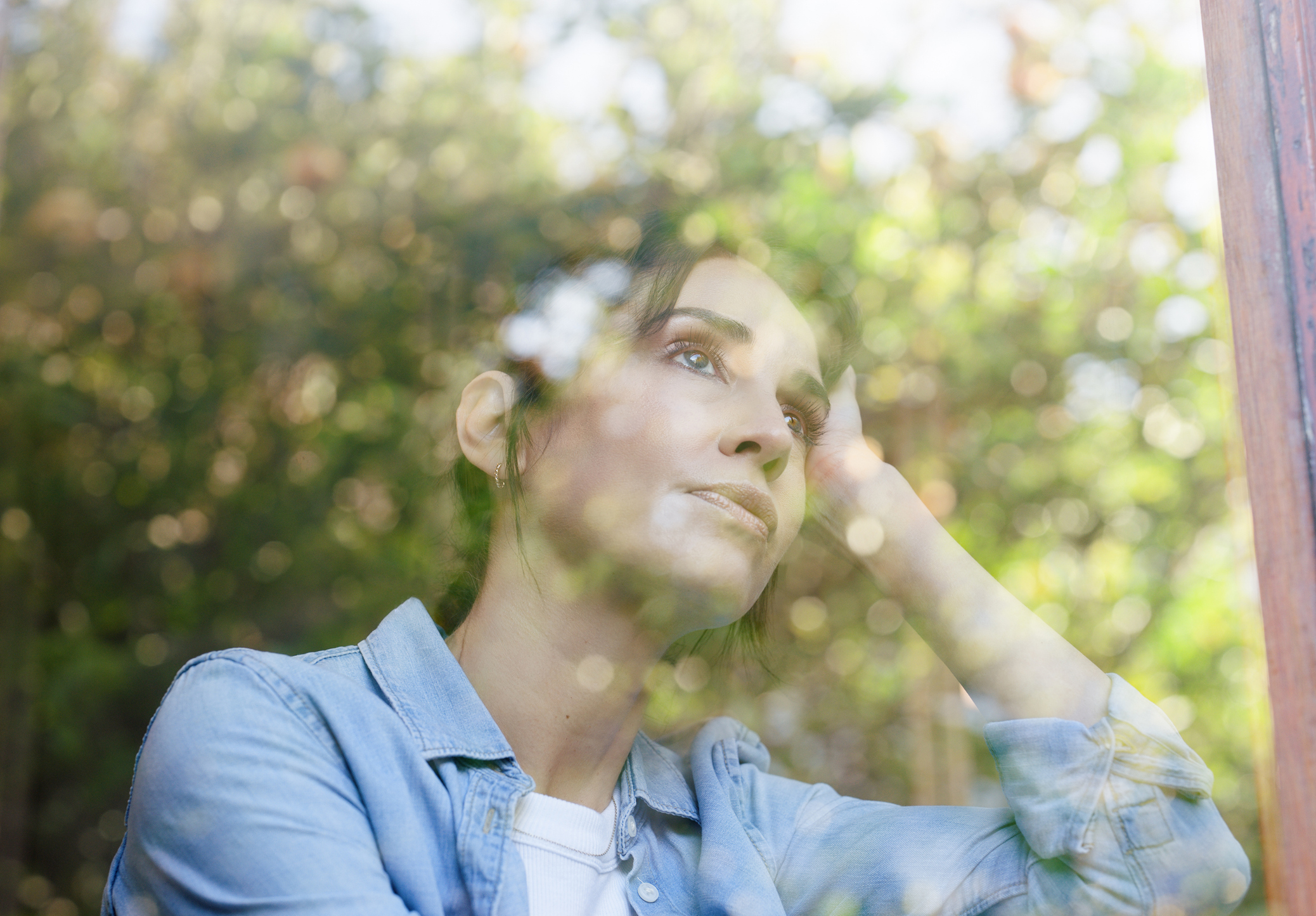 Young white woman looking stressed. The reflection of a window overlays her in the image