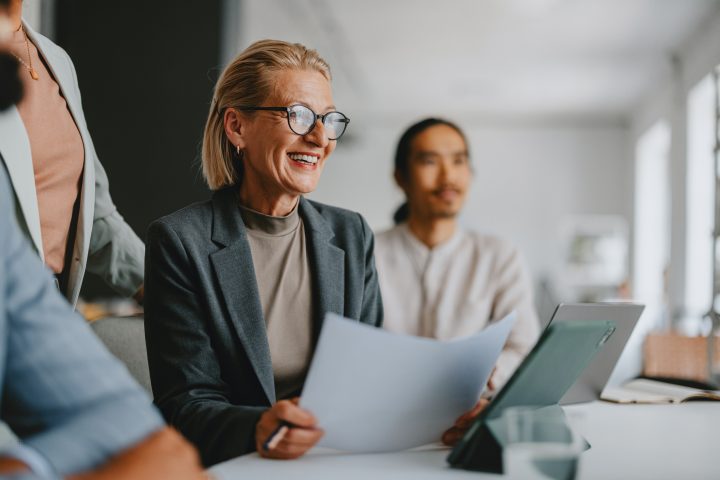 Confident senior businesswoman leading a team during an office meeting, showcasing collaboration and leadership in a professional workplace environment