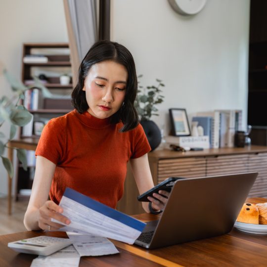 Woman doing personal finances on laptop, making invoices, calculating business expenses
