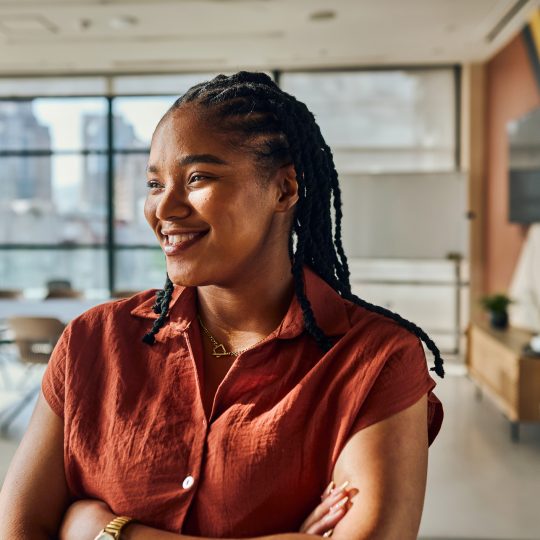 Portrait of a young black female software engineer smiling with crossed arms,