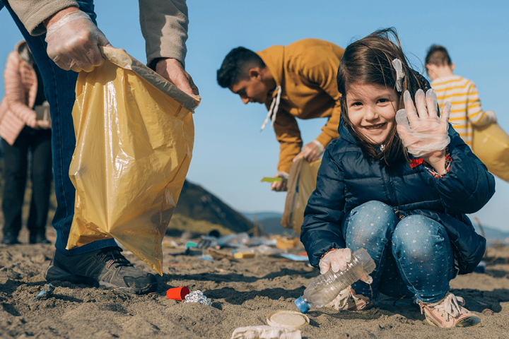 Child litter-picking at the beach with adults
