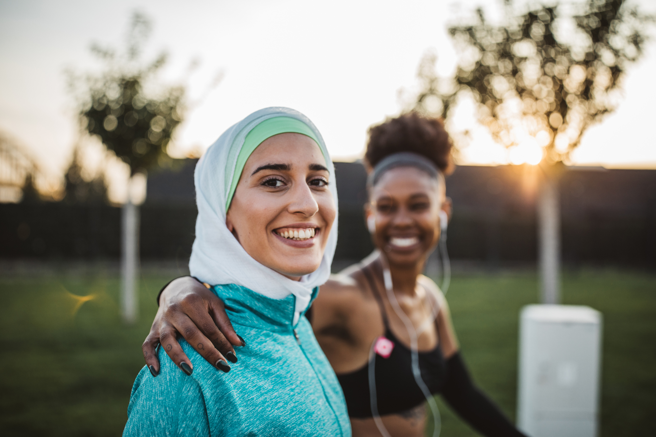 Two young women, different ethnicity ,exercisng outdoor. They are wearing sport clothing. Getting ready for training.