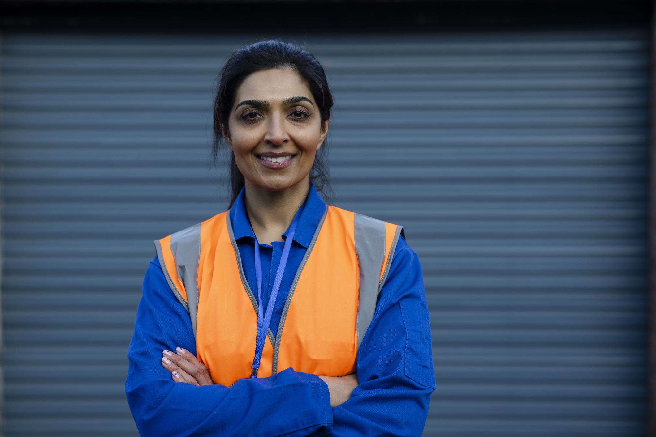 Female worker smiling, wearing coveralls looking at the camera.