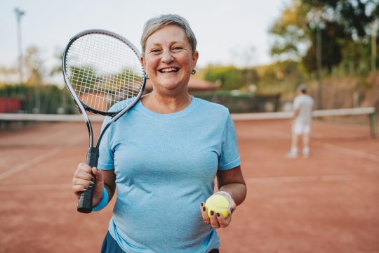 Portrait of an elderly woman holding a tennis racket